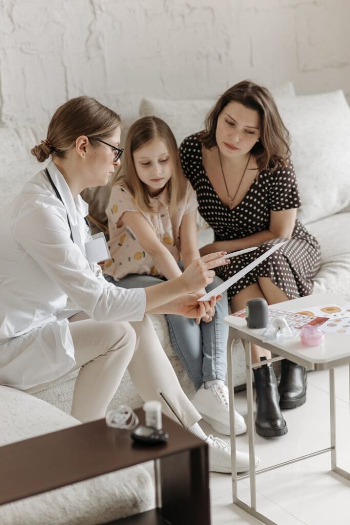 pexels-photo-7653110 Doctor discussing health care plan with mother and daughter on sofa.